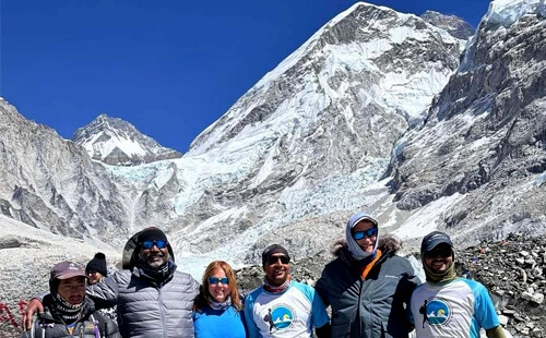 A small group of trekkers with a professional guide clicking pictures of Mt. Everest as a backdrop.